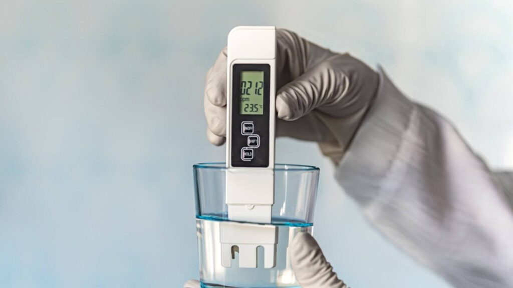 A hand shown testing the hardness of the water in a glass